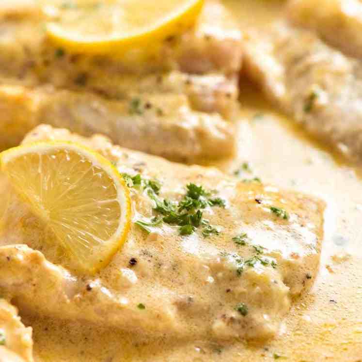 Close up photo of Baked Fish with Lemon Cream Sauce in a white pan, fresh out of the oven
